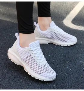 Dettaglio delle scarpe da corsa in mesh traspirante bianco su una pista sportiva