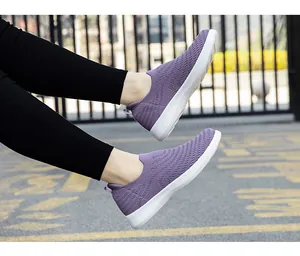 Close-up of purple breathable fly-knit slip-on walking shoes on an outdoor pavement
