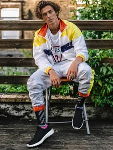 Outdoor Streetstyle mit farbenfrohem Windbreaker, weißer Jogginghose und Sneakern