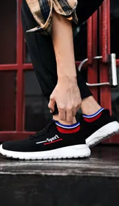 Detailansicht eines schwarzen atmungsaktiven Sneakers mit gestricktem Bündchen und weißer Sohle