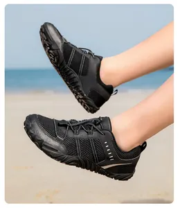 Detalle de zapatos de agua de malla negra con suela de goma antideslizante en la playa