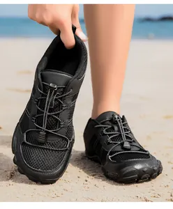 Detalle de zapatos de agua negros con malla de panal y suela de goma en la playa arena