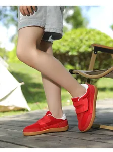 Close-up of kids red velcro sneakers with durable gum rubber soles on outdoor grass
