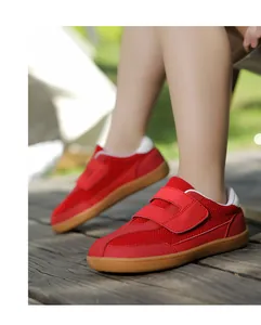 Detail of red kids sneakers with double hook-and-loop straps and brown rubber sole