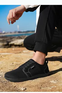 Detailansicht atmungsaktiver schwarzer Sneaker aus Fly-Knit auf felsigem Strand im Freien