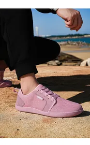 Außenaufnahme eines rosa Mesh- und Wildleder-Sneakers auf felsigem Strandgelände