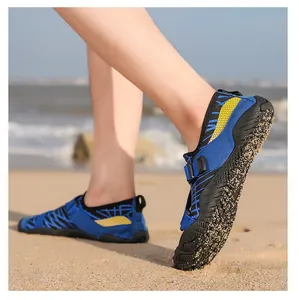 Close-up of non-slip rubber sole on blue and yellow water shoes at the sandy beach