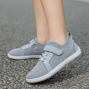 Close-up of kids light grey breathable mesh sneaker with velcro strap on gravel ground