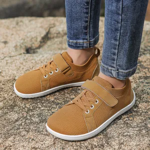 Detailed outdoor shot of ginger mesh kids sneakers with velcro straps on stone background