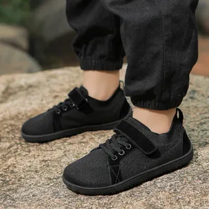 Detail view of black kids sports shoes with mesh upper and velcro strap on rocks
