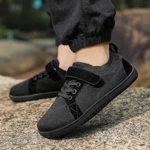 Close-up of kids black breathable mesh sneakers with velcro straps on outdoor rocks