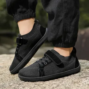 Close-up of black breathable mesh kids' sneakers with velcro strap on a rocky terrain