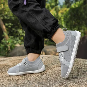Close-up of breathable light gray kids mesh sneakers with velcro straps on outdoor rocks