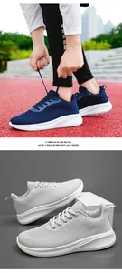 Gros plan de chaussures de course en maille respirante bleu marine et gris à semelles blanches