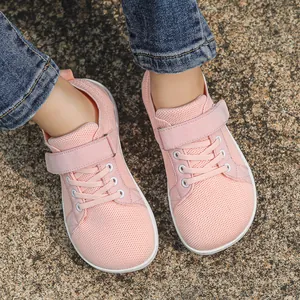 Close-up of pink breathable knit mesh kids sneakers with velcro straps on stone path