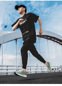 Dynamic street shot of grass green breathable running shoes paired with black sports joggers