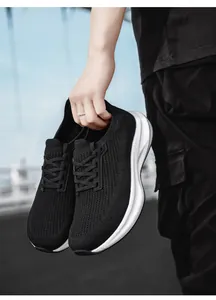 Detail of black mesh breathable sneaker with thick white cushioned sole held by a model