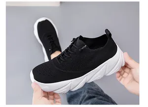 Close-up detail of breathable black knitted mesh upper and white wave-patterned thick sole