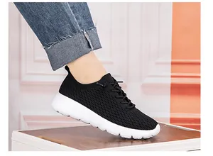 Side view of lightweight knit breathable sneakers with thick white soles on a person