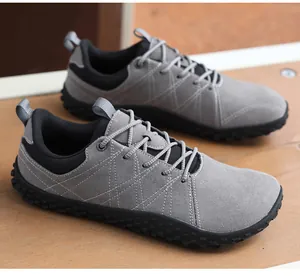Dettaglio delle scarpe a piedi nudi grigio scuro con cuciture a croce su tavolo in legno