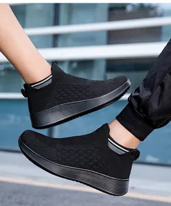 Detailed texture of black knit slip-on sneakers with elastic striped ankle cuffs