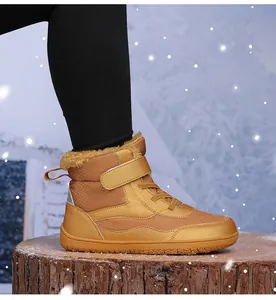Close-up of children's warm high-top snow boots with ginger fur lining on a snowy log
