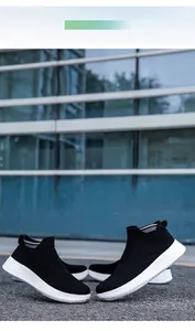 Detail of couple wearing breathable black knitted slip-on sneakers with white soles