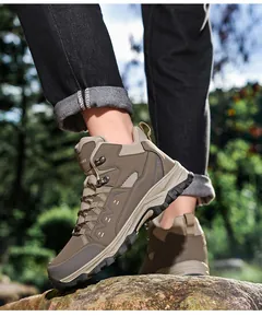 Macro detail of men's hiking boots showing rugged traction sole on outdoor rocks