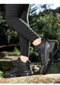 Detail of black tactical hiking boots with non-slip rubber soles in outdoor terrain