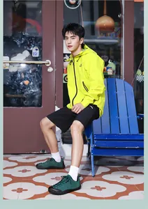 Coupe-vent homme vert néon avec short noir et chaussures de randonnée vert foncé