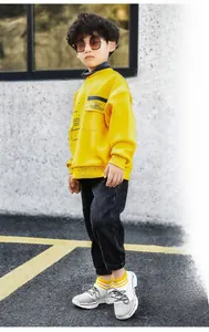 Dettaglio della felpa gialla con tasca e pantaloni neri casual per bambini