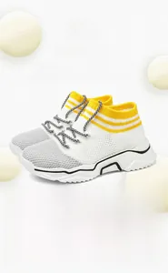 Dettaglio del tessuto a maglia giallo e bianco e lacci a fantasia su scarpa bimbo