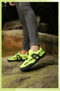 Outdoor trail view of neon green water shoes with non-slip rubber soles on rocky terrain