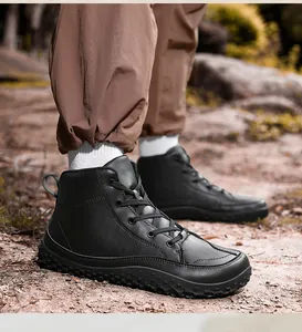 Primer plano de botas de senderismo de cuero negro con suelas antideslizantes sobre terreno