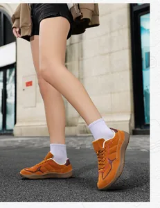 Outdoor low-angle shot of ginger hiking sneakers with deep red wavy trim and rubber soles