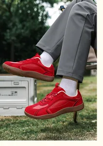 Primer plano de zapatilla roja de ante con suela de goma sobre césped verde