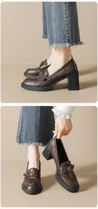 Details dunkelbrauner Leder-Loafer mit goldener Schnalle und Blockabsatz zu Jeans
