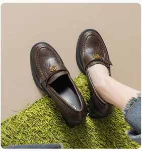Detail eines braunen Leder-Loafers mit goldener Kamelien-Schnalle und klobiger Sohle