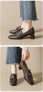 Gedetailleerd zicht op donkerbruine vintage leren loafers met gouden metalen gesp detail