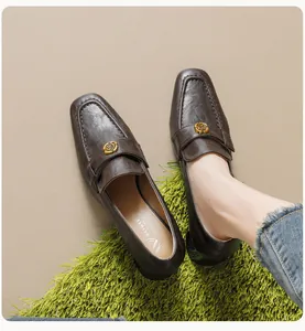 Detail van donkerbruine lederen loafers met een gouden metalen gesp en zachte textuur