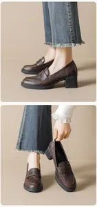 Detail of dark brown platform loafers with thick block heels paired with denim pants