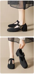 Détail de chaussures Mary Jane en daim noir avec bride en T et boucle dorée