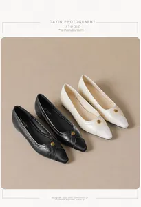 Detail of pointed-toe flats in black and beige with elegant gold flower ornaments