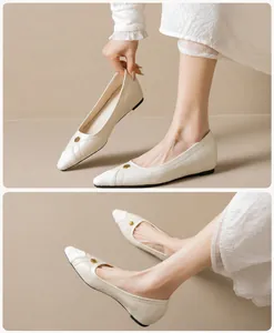 Close-up of cream pointed-toe flat shoes with gold floral metal buckle and textured toe detail