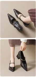 Close-up of black glossy Mary Jane shoes with gold chain buckle and block heels