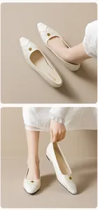 Detailed view of beige pointed-toe flat with gold rose buckle and textured toe cap