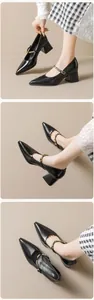 Detail view of black pointed-toe Mary Jane pumps with block heels and metallic buckles