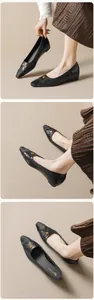 Detail of black pointed-toe flat shoe featuring a matte toe cap and gold rose buckle decoration