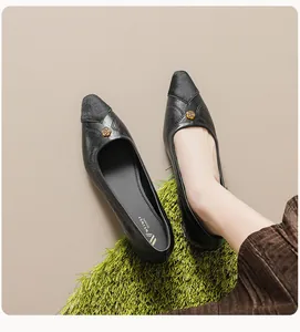 Detailed top view of black pointed toe flat shoe with golden floral metal buckle