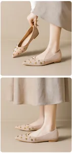 Close-up of beige suede pointed flats with gold star rivets and elegant studded details